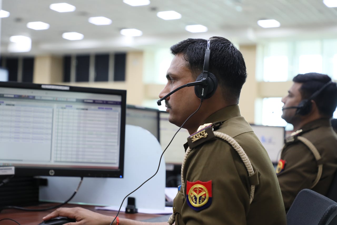 Indian police officers working at a dispatch center, focused and equipped with headsets.